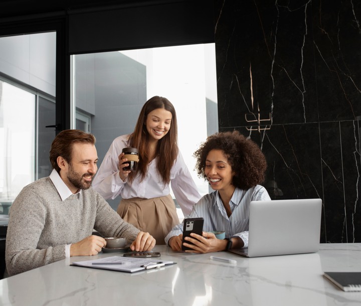 people around table looking at a laptop