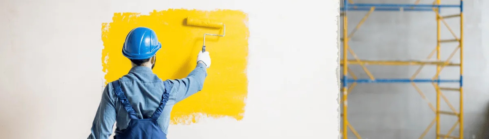 painter painting a wall with yellow pain